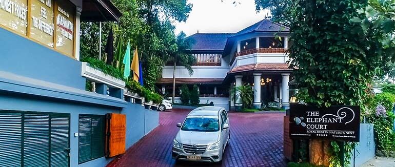 The Elephant Court hotel entrance with a silver car on the paved driveway.