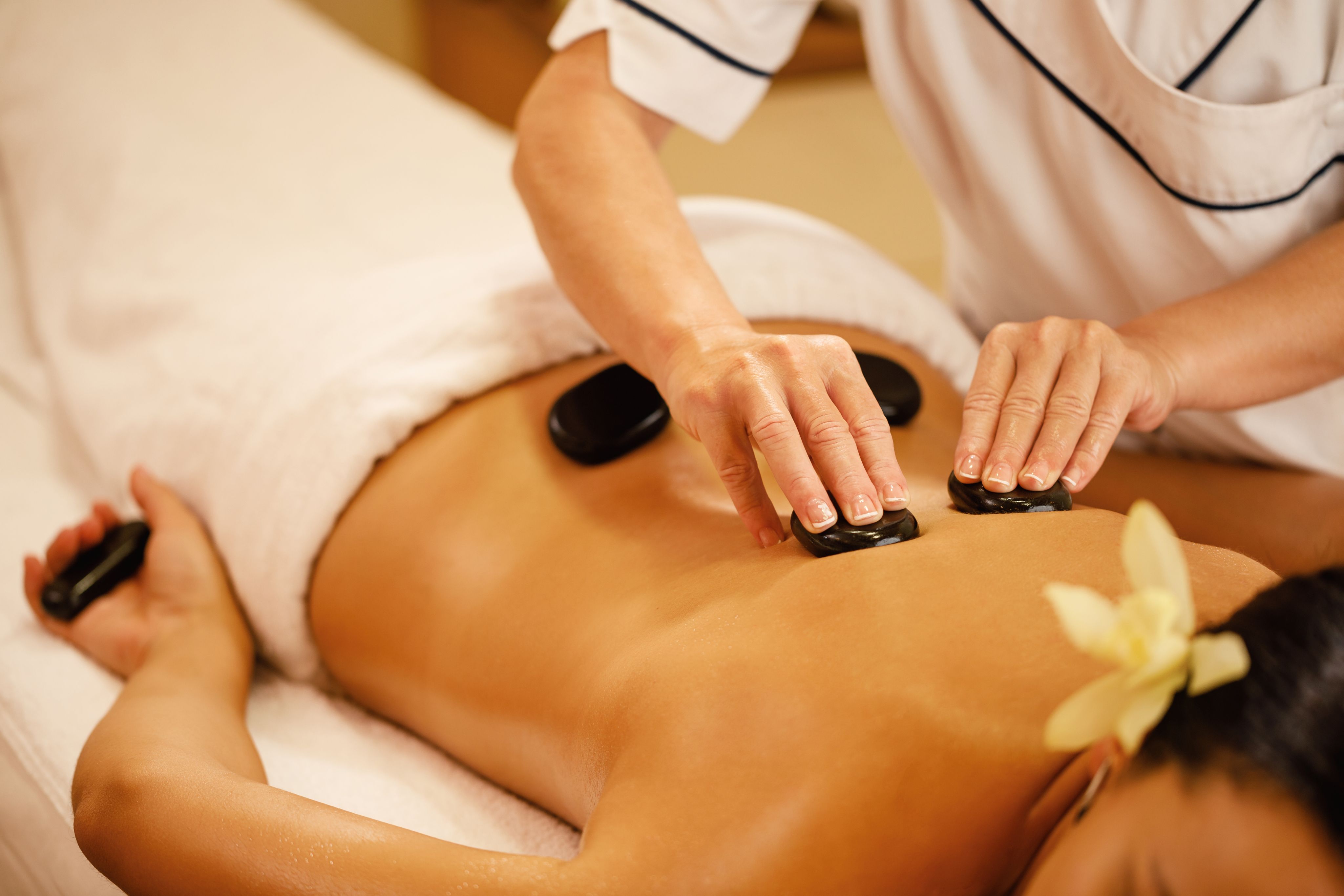 Person receives a hot stone massage on their back at a spa.