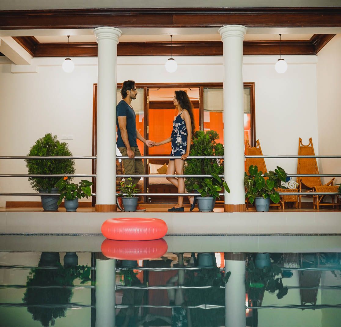 Couple standing on resort balcony overlooking swimming pool